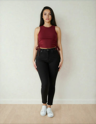 Femme debout, portant un crop top bordeaux et un pantalon noir, mode tendance 974 Réunion