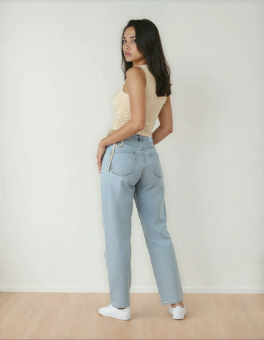 Femme portant un jean taille haute bleu clair et débardeur beige, mode 974 Réunion