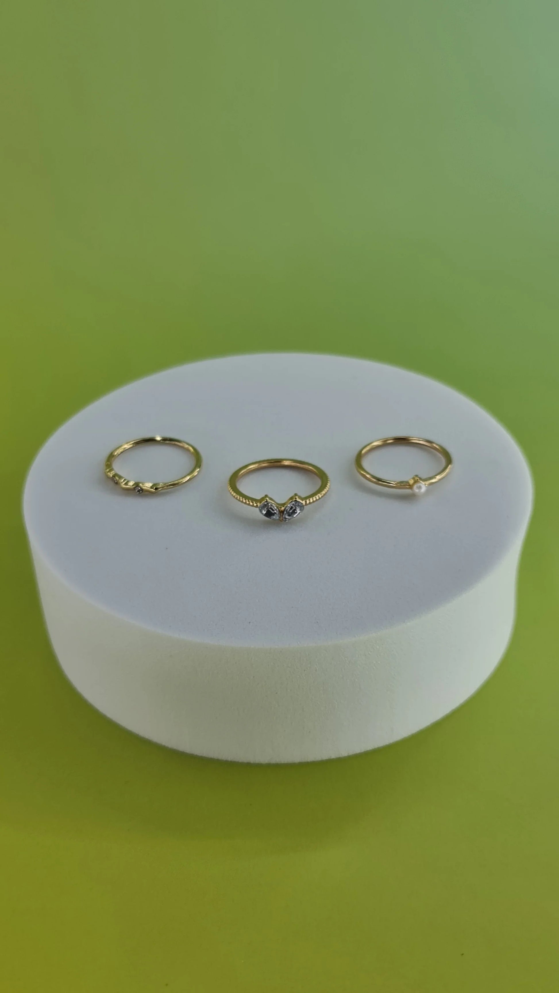 Trois bagues fines dorées sur support blanc, fond vert, bijoux femme 974 Réunion