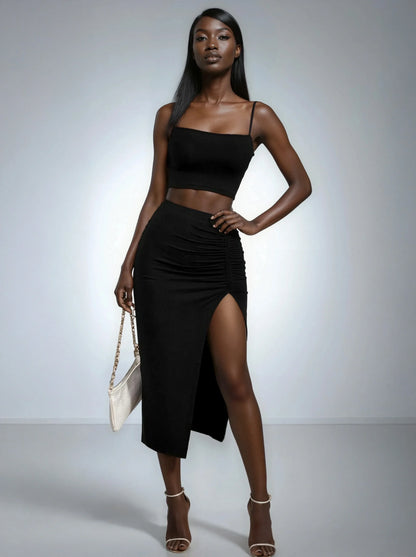 Femme portant un ensemble noir élégant, jupe fendue et crop top, sac à main, 974 Réunion